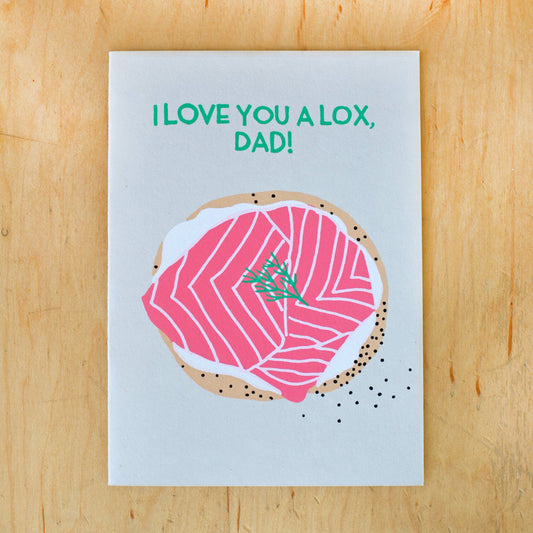 Card reads "I love you a lox, dad!" and has illustration of a bagel with cream cheese, lox and dill on it 