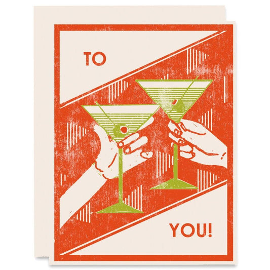 Red letterpress greeting card with two hands holding two  green martini glasses on it 