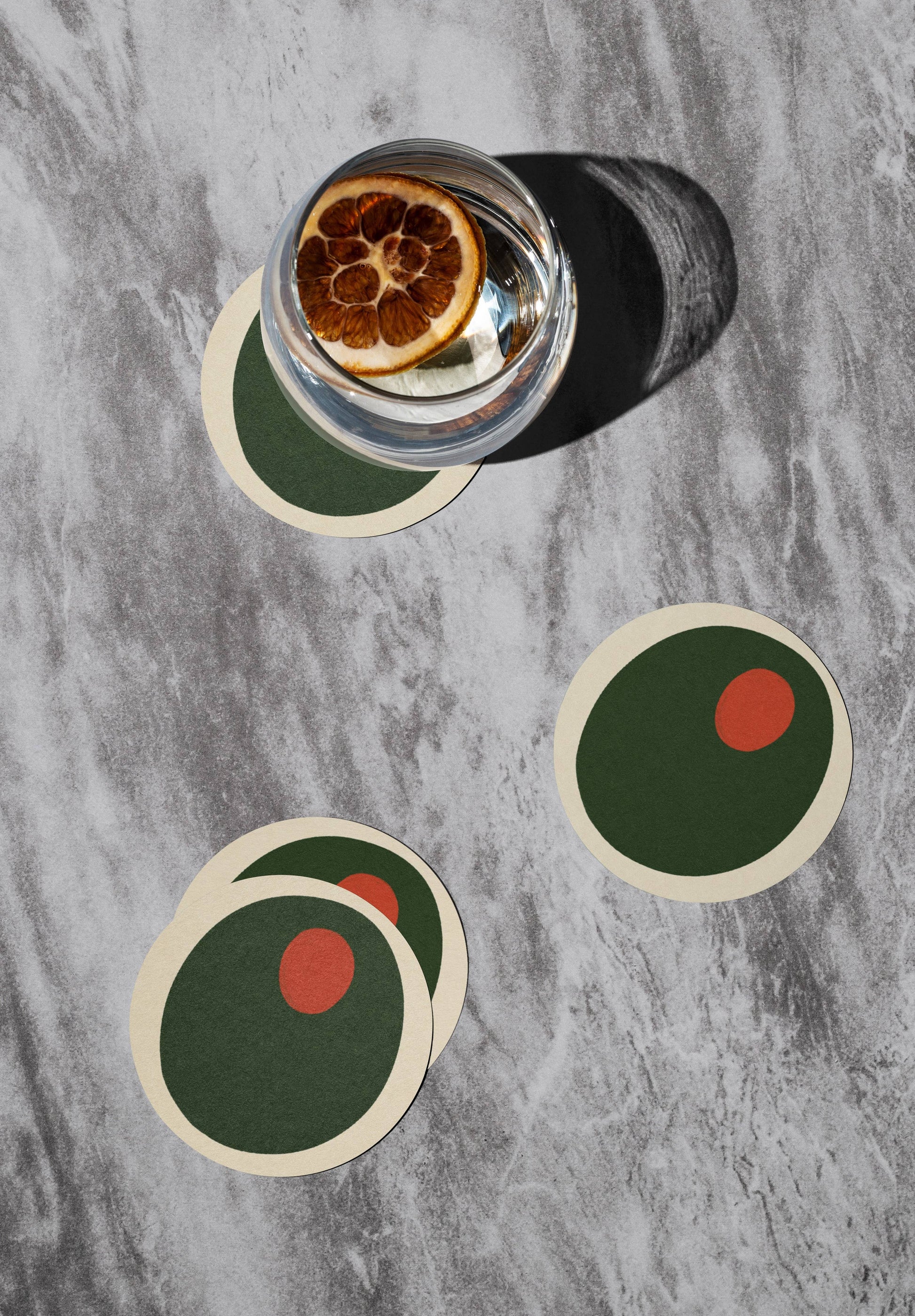 Pimento olive coasters on tabletop with a drink on one of them 