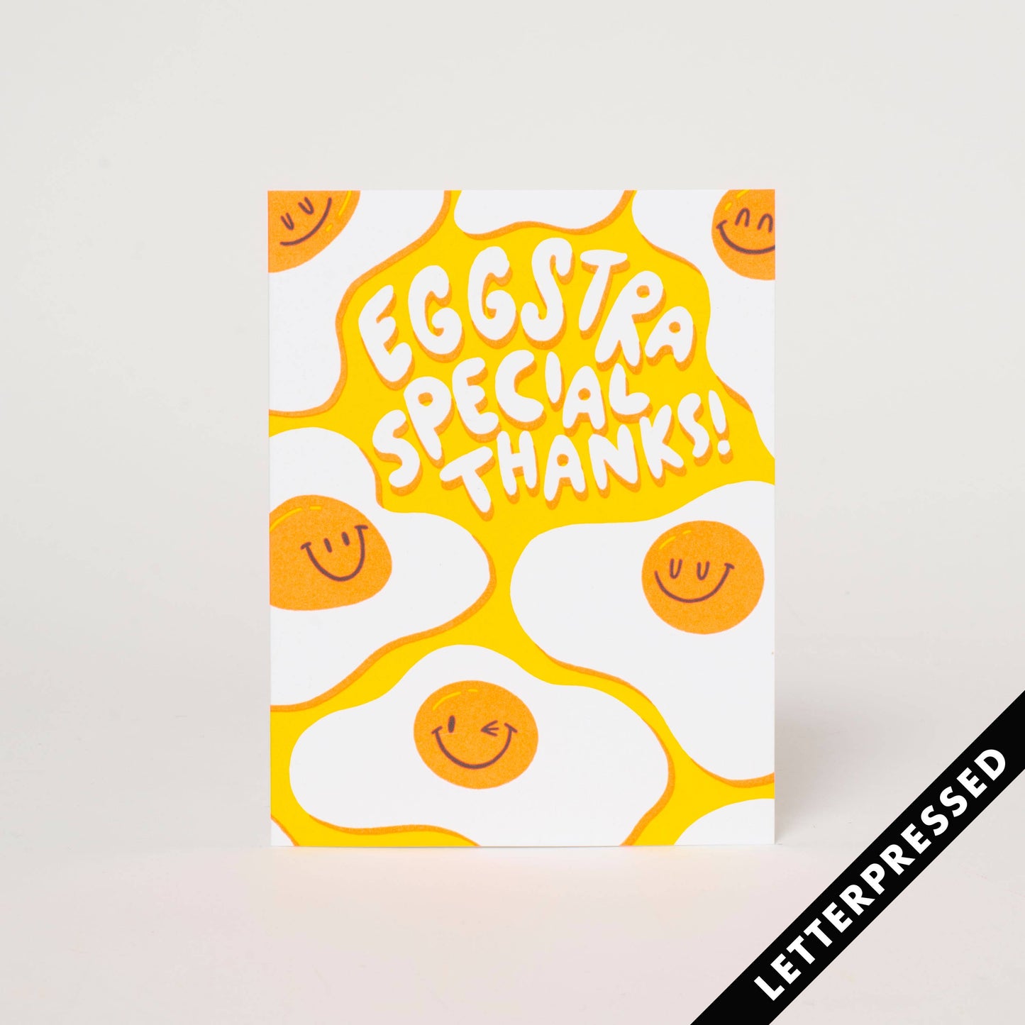Letterpress printed greeting card with image of smiling fried eggs on bright yellow background and text "Eggstra Special Thanks!"