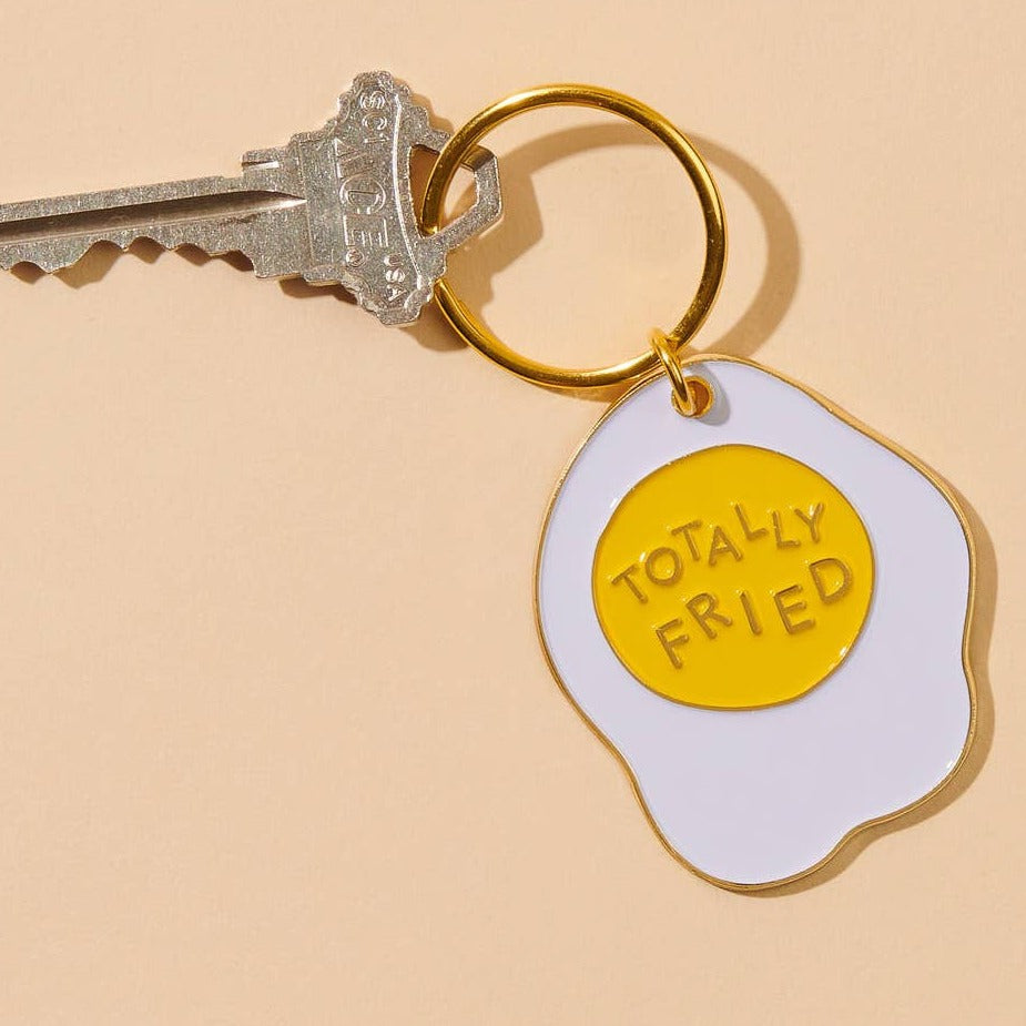 Enamel keychain of an egg that says Totally Fried.