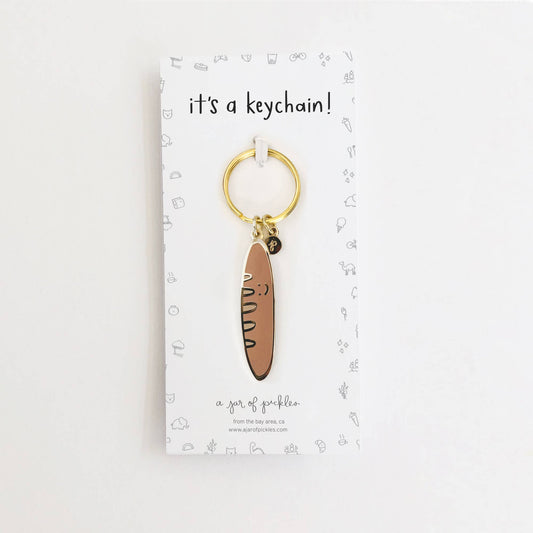 Card backing that reads "it's a keychain!" and a baguette keychain on a gold ring.