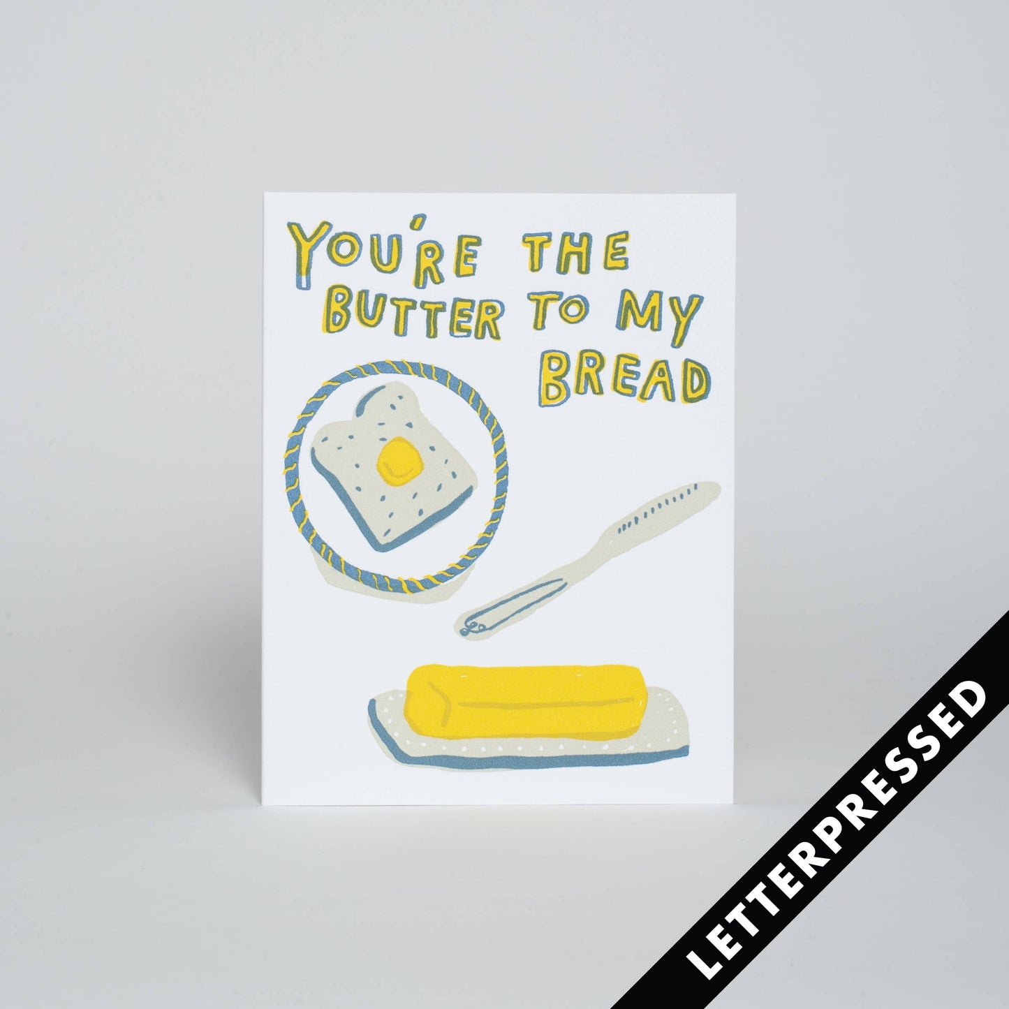 Greeting card that reads "You're the butter to my bread" up top. Images on the card include a slice of toast with butter on a plate, butter knife and stick of butter. 