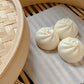 Decorative candles shaped like Chinese Bao (steamed buns) shown in a traditional bamboo steamer basket.