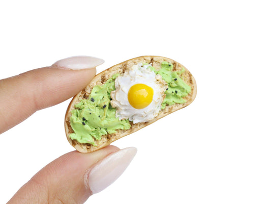 Mini avocado toast magnet with cracked pepper and a fried egg.