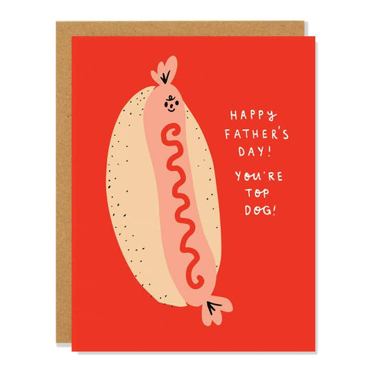 Red greeting card with an illustration of a pink hot dog, with ketchup, in a bun. To the right of that it reads "Happy Father's Day! You're top dog!" Comes with a brown (kraft) envelope. 