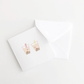 White mini greeting card with white envelope. On the front of the card are two boba cups smiling at each other. 