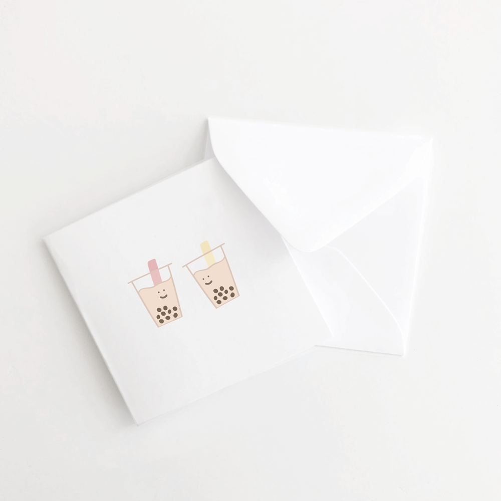 White mini greeting card with white envelope. On the front of the card are two boba cups smiling at each other. 