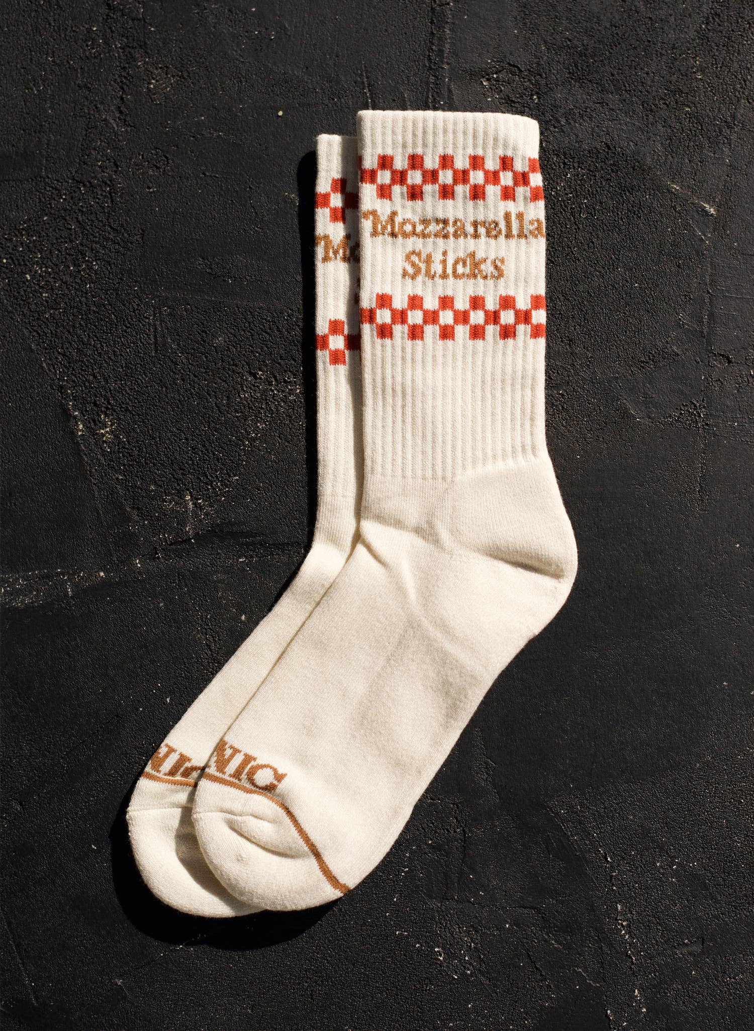 Cream colored socks -- on ribbed, ankle part it reads "Mozzarella Sticks" in between red and cream checker print 