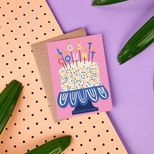 Birthday greeting card with a huge cake with candles that spell out LOST COUNT