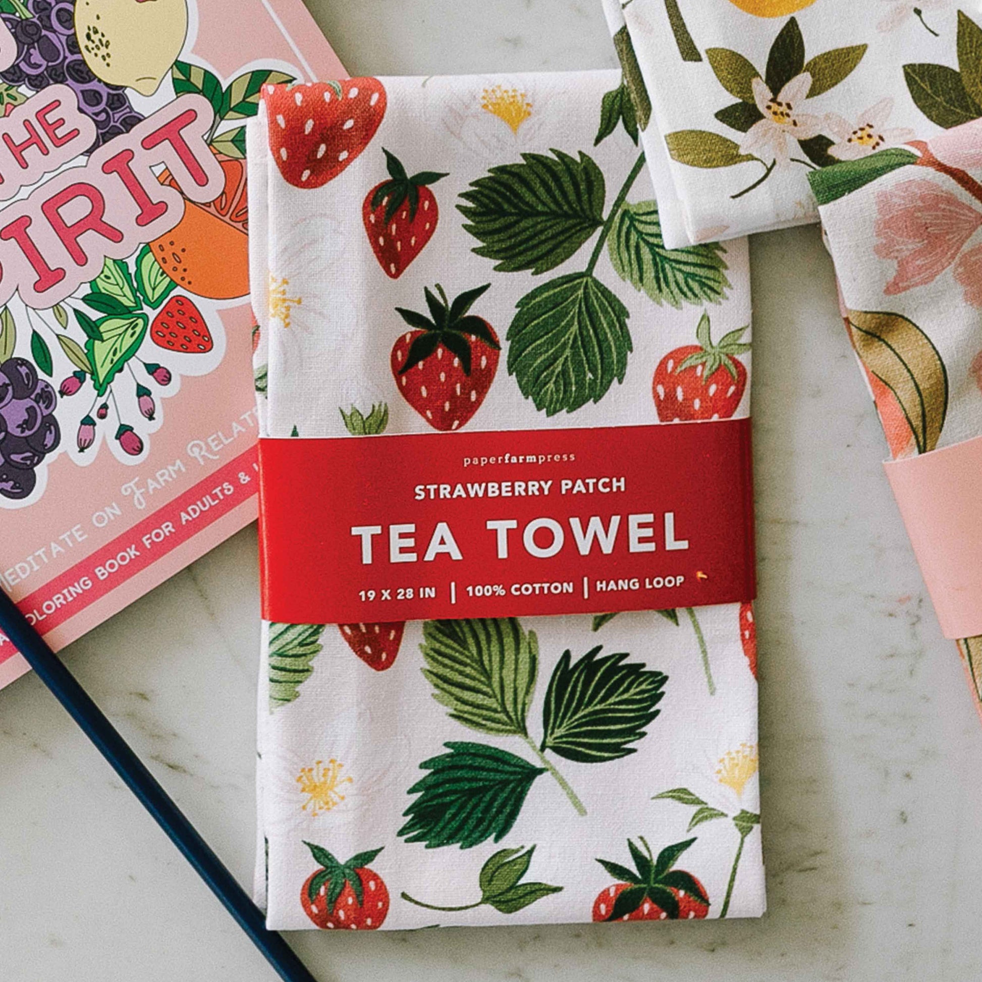Tea towel in strawberry patch print, shown in packaging 