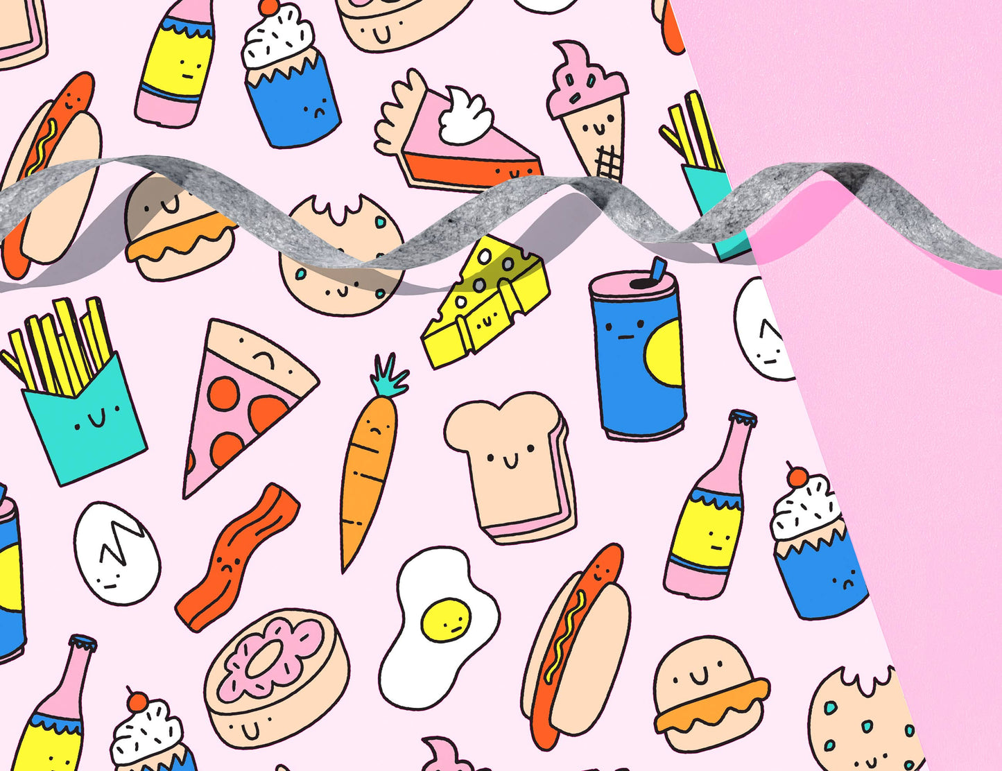 Wrapping paper with various, colorful snack foods on it including hot dogs, fries, pizza, bacon, eggs, carrots, cheese, sandwiches, pie and drinks 