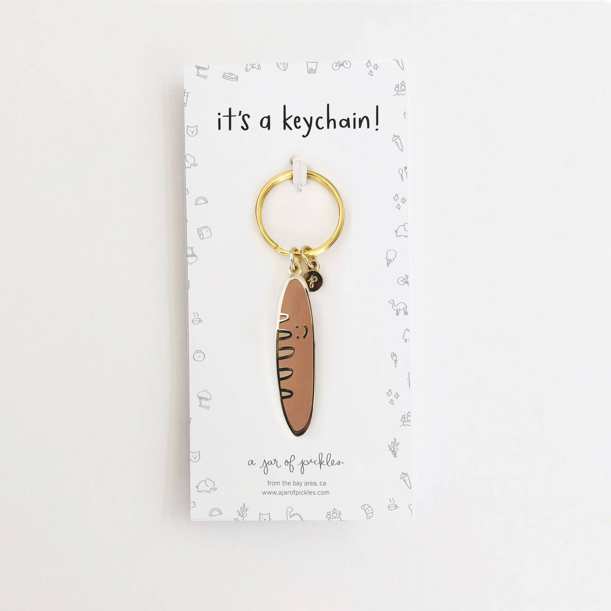 Card backing that reads "it's a keychain!" and a baguette keychain on a gold ring.