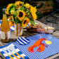 table setting featuring a blue gingham placemat with a bright red lobster and lemon embroidered on 