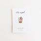 Boba cup enamel pin with a smiley face, placed on white card backing that says "it's a pin!"