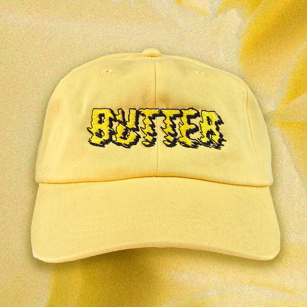 Butter yellow cap -- a Mister Parmesan x Milkfarm collaboration -- has BUTTER embroidered in yellow and black on the front 