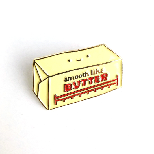 Butter enamel pin -- along with a face on it, it reads "Smooth like butter" 