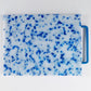 mostly white cutting board with blue confetti throughout, handle is blue 