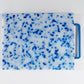 mostly white cutting board with blue confetti throughout, handle is blue 