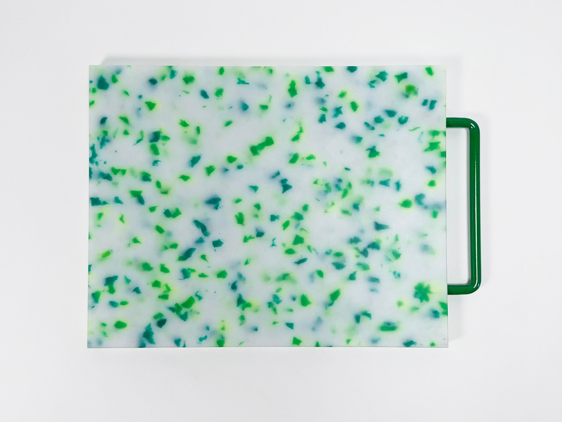 mostly white cutting board with blue and green confetti throughout, handle is green 
