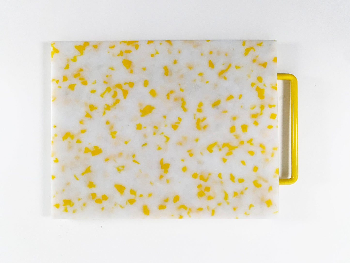 Mostly white cutting board with yellow confetti throughout, handle is yellow