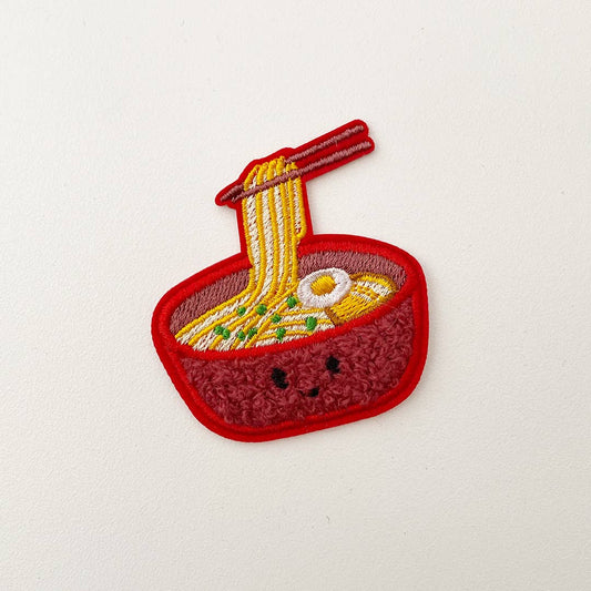 Ramen chenille patch with chopsicks pulling ramen out of the bowl. 