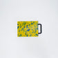 Small yellow cutting board with blue confetti and black handle 