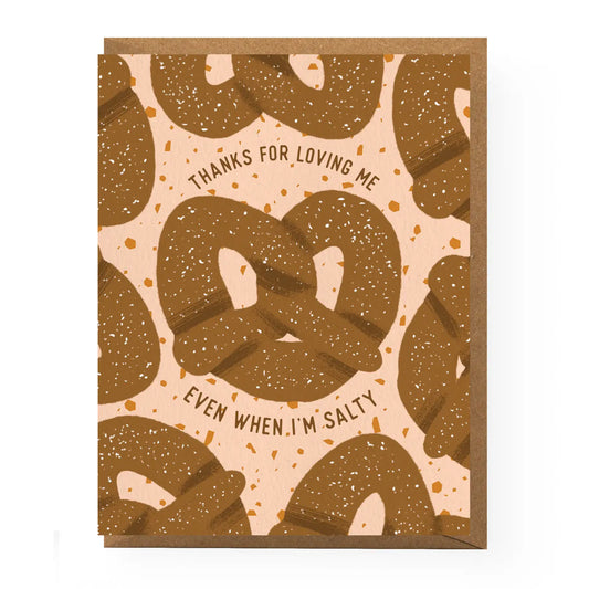 Greeting card with pretzels on a mostly pink background with pretzel crumbs for the design. In the center it reads "Thanks for loving me even when I'm salty" Comes with brown kraft envelope. 