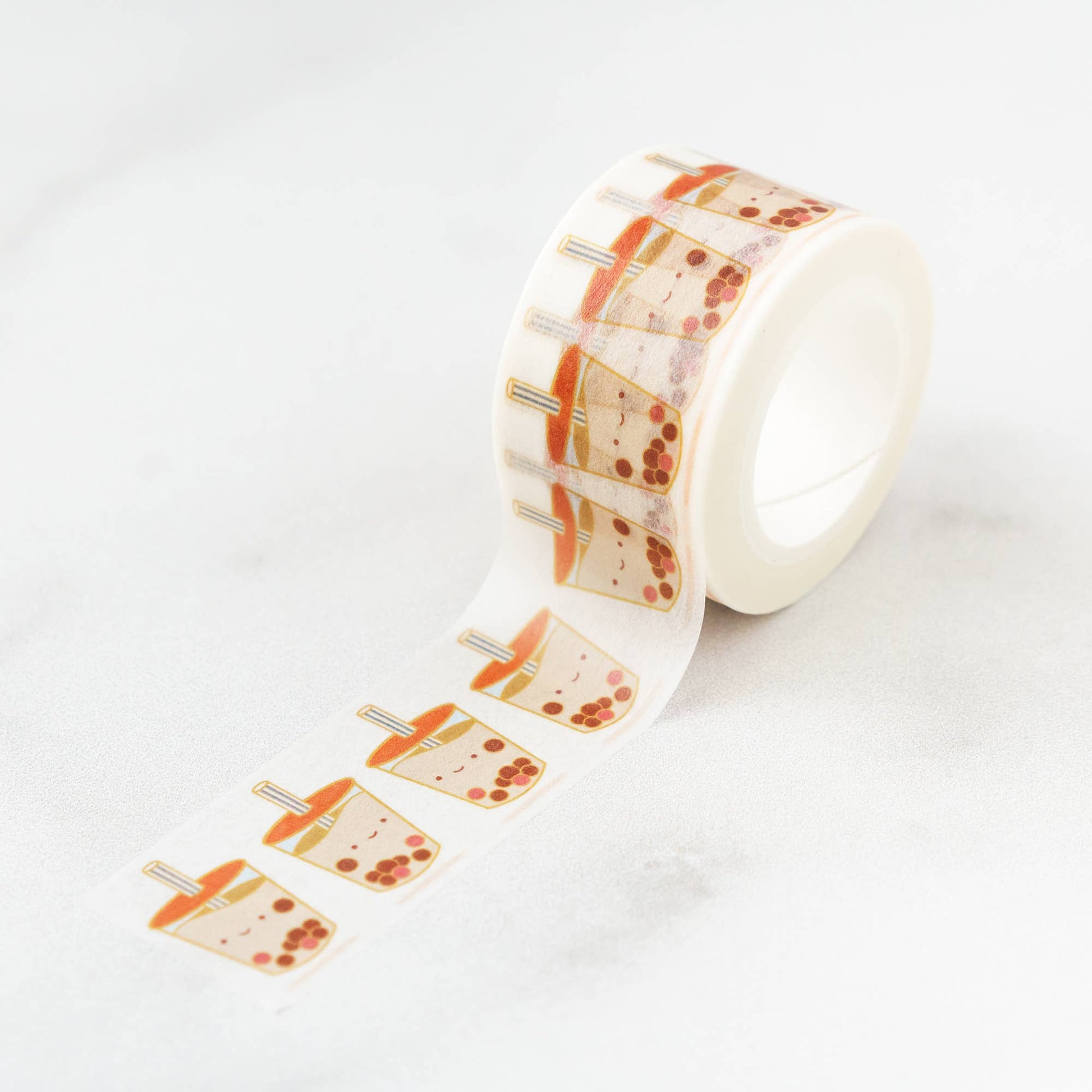 Roll of washi tape unraveled to reveal the boba cup pattern. Boba cups have smiley faces, red lids, and striped straws.