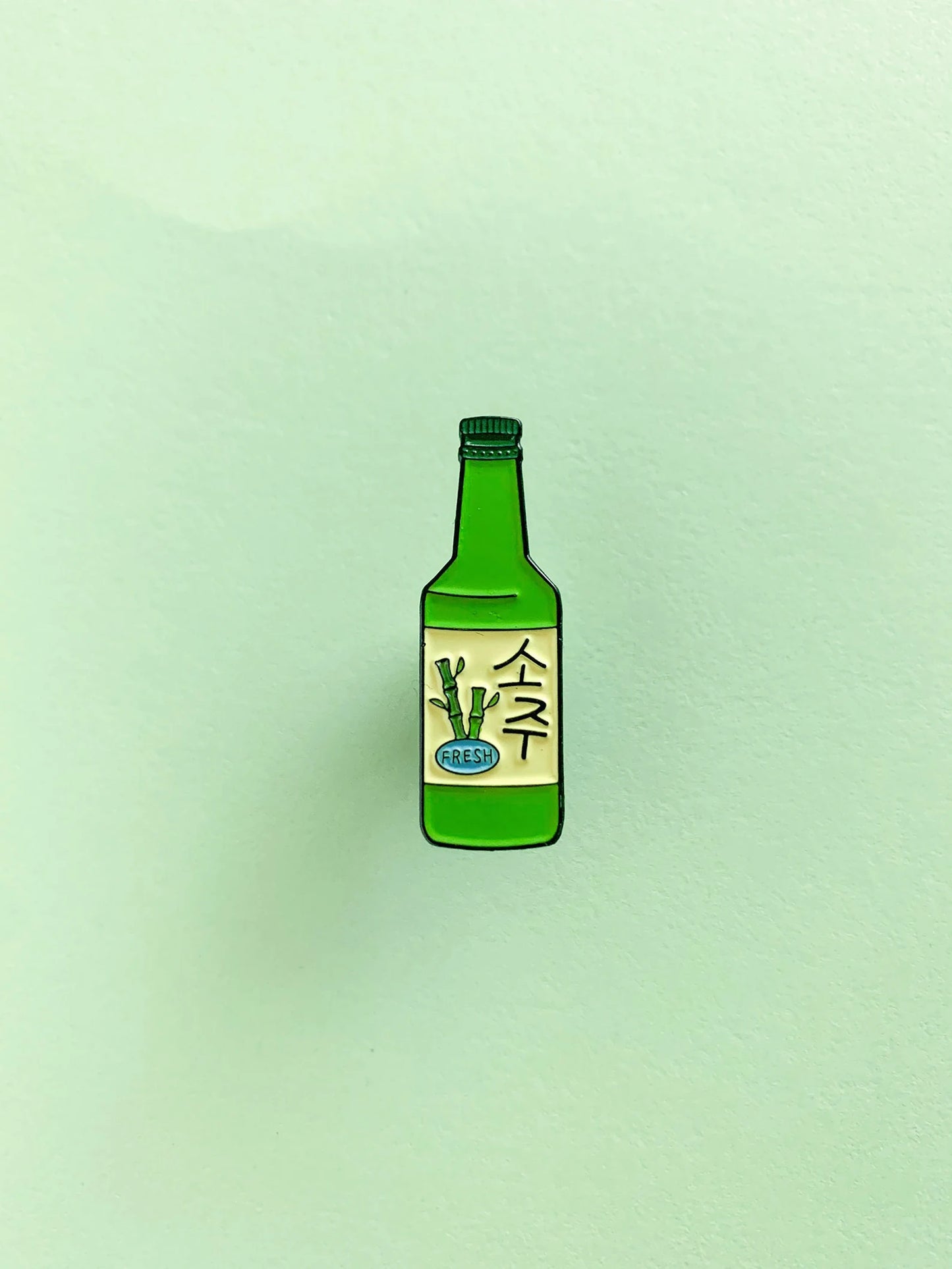 Enamel pin of a green soju bottle