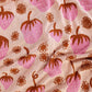close up view of knit blanket in sorbet --- dark pink strawberries and dark orange flowers as the overall print on top of a light pink background. 