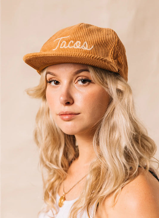 Tan colored, corduroy cap with "Tacos" embroidered on the front on model 