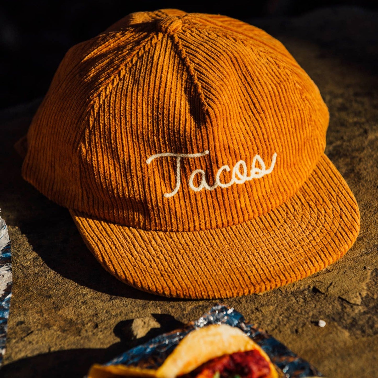 Tan colored, corduroy cap with "Tacos" chainstitched on the front 