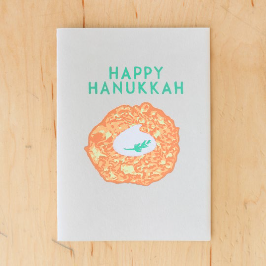 Greeting card that reads "Happy Hanukkah" and has the image of a latke with sour cream on it 