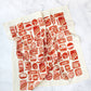 White tea towel designed with variously shaped, red, tin sardine cans.  