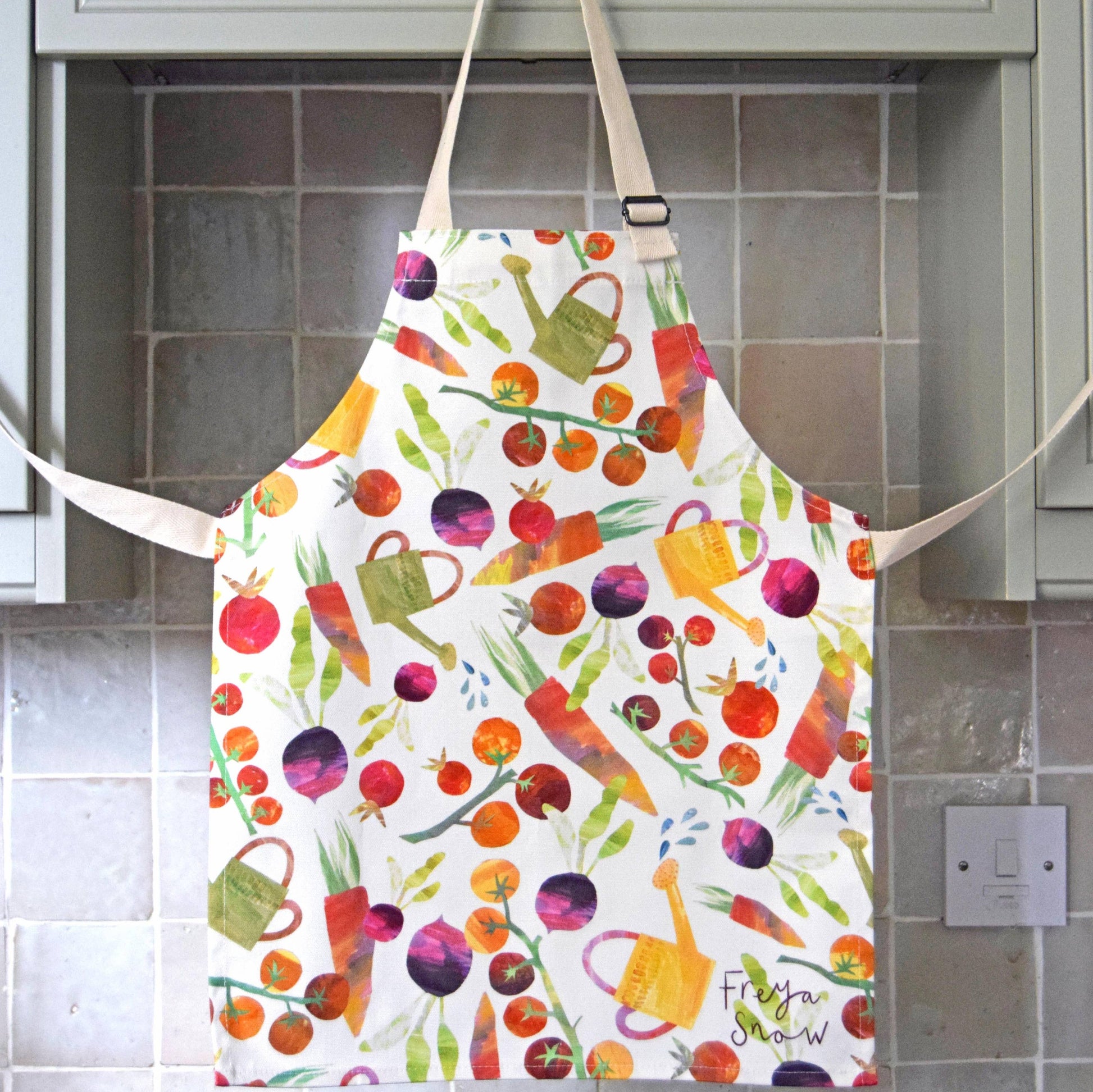 Children's apron with different garden vegetables and watering cans on it 