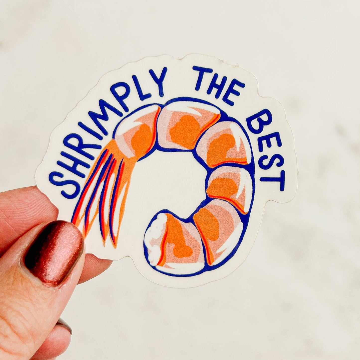 transparent sticker with a piece of shrimp and words that say "Shrimply the Best"