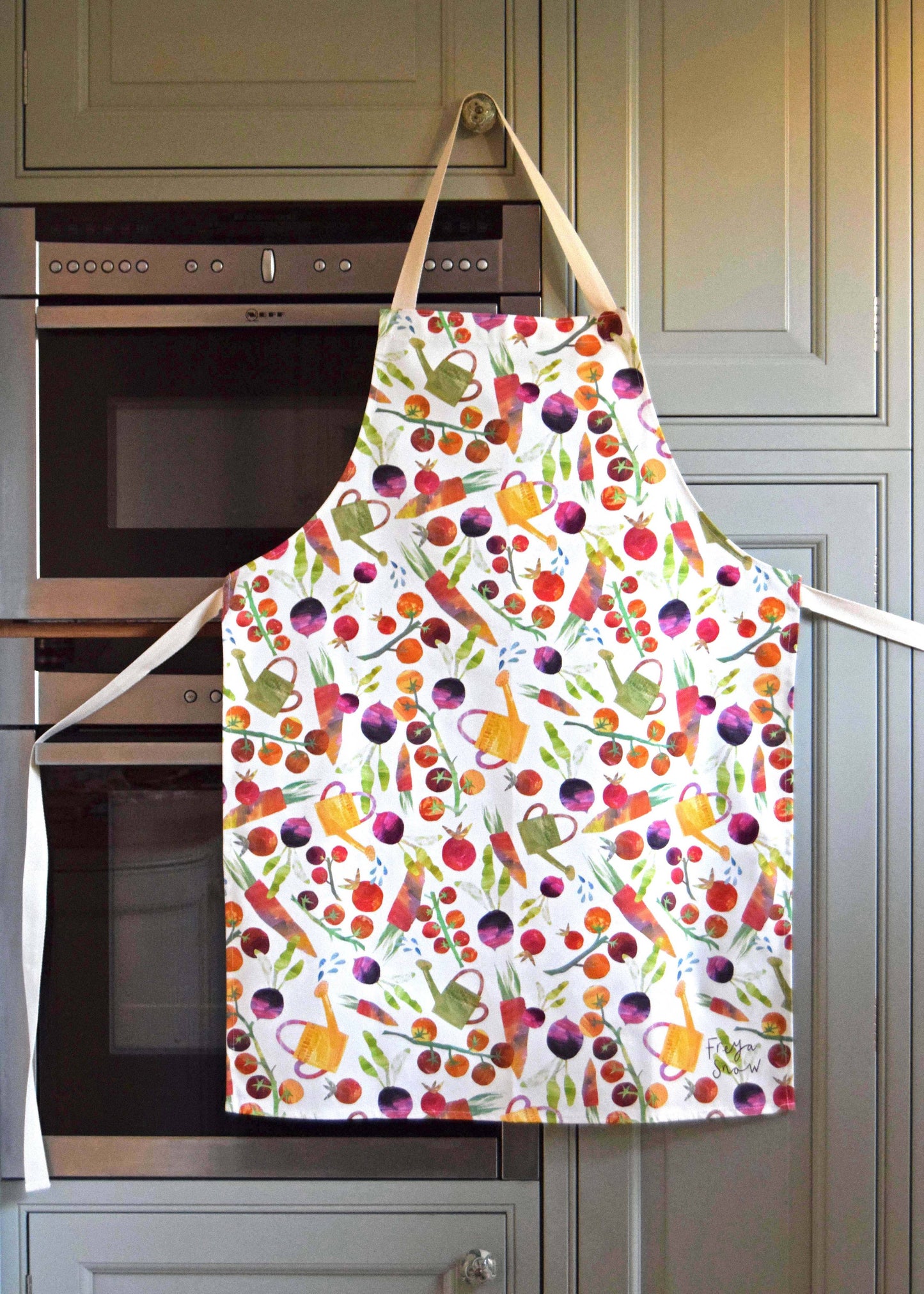 Adult size apron with various garden vegetables and watering cans on it 