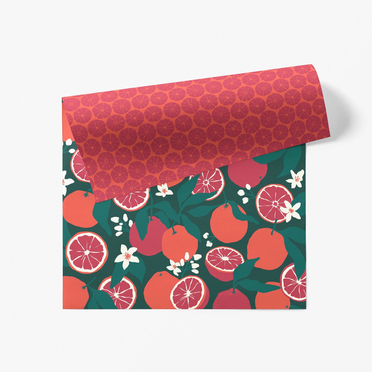 Sheet of double-sided wrappng paper -- one side is dark green with blood oranges, the other is orange with dark red citrus slices 