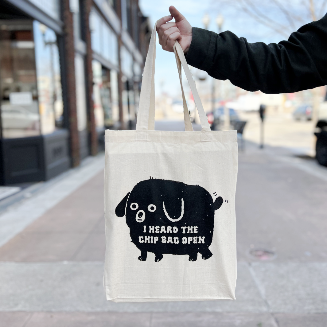 Tote bag with black dog on it that reads "I heard the chip bag open" 
