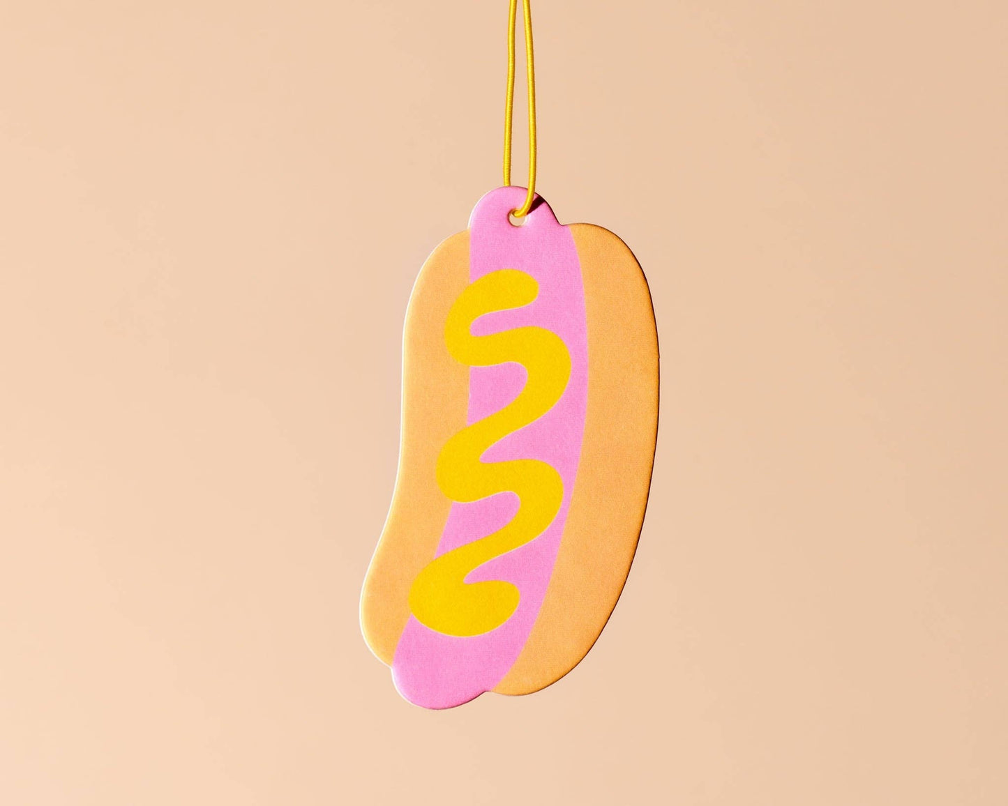 Double sided car air freshener made to look like a hot dog. Has sliver of mustard on it. 