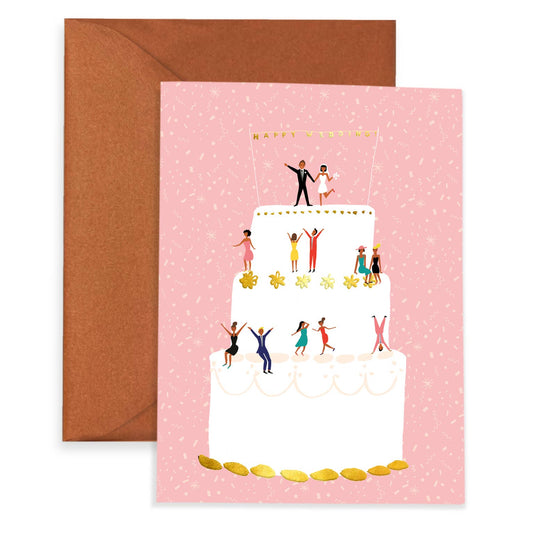 Pink greeting card with a 3 tier wedding cake on it. Bride and groom are atop the first tier with guests lining each of the other two tiers. Above the bride and groom is a banner that reads "Happy Wedding"
