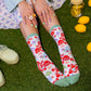 Mushroom socks with forest green toe and heel. Model is sitting on astroturf with rings on her fingers and lemonade