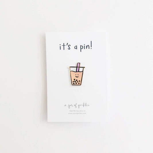 Boba cup enamel pin with a smiley face, placed on white card backing that says "it's a pin!"