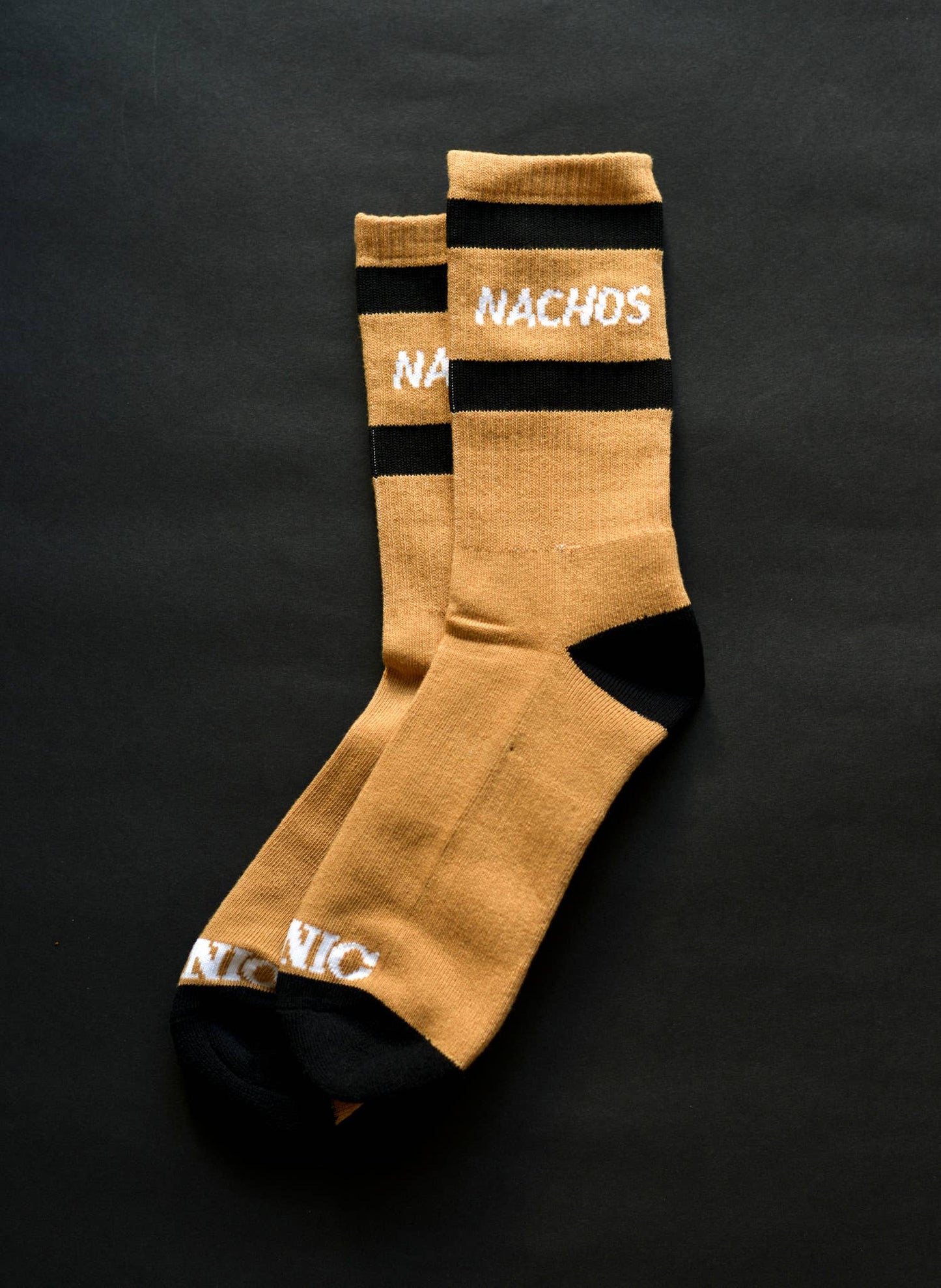 Socks. NACHOS written between two black lines in white words. Black fabric on the heal and toe. 