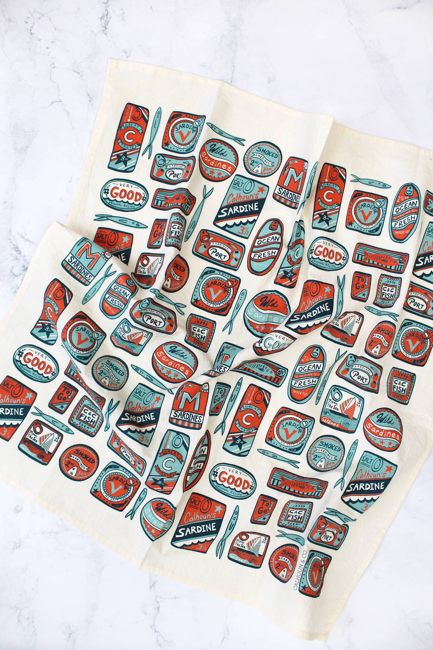 White tea towel with various shaped sardine tin cans in a light blue, navy and red colorway