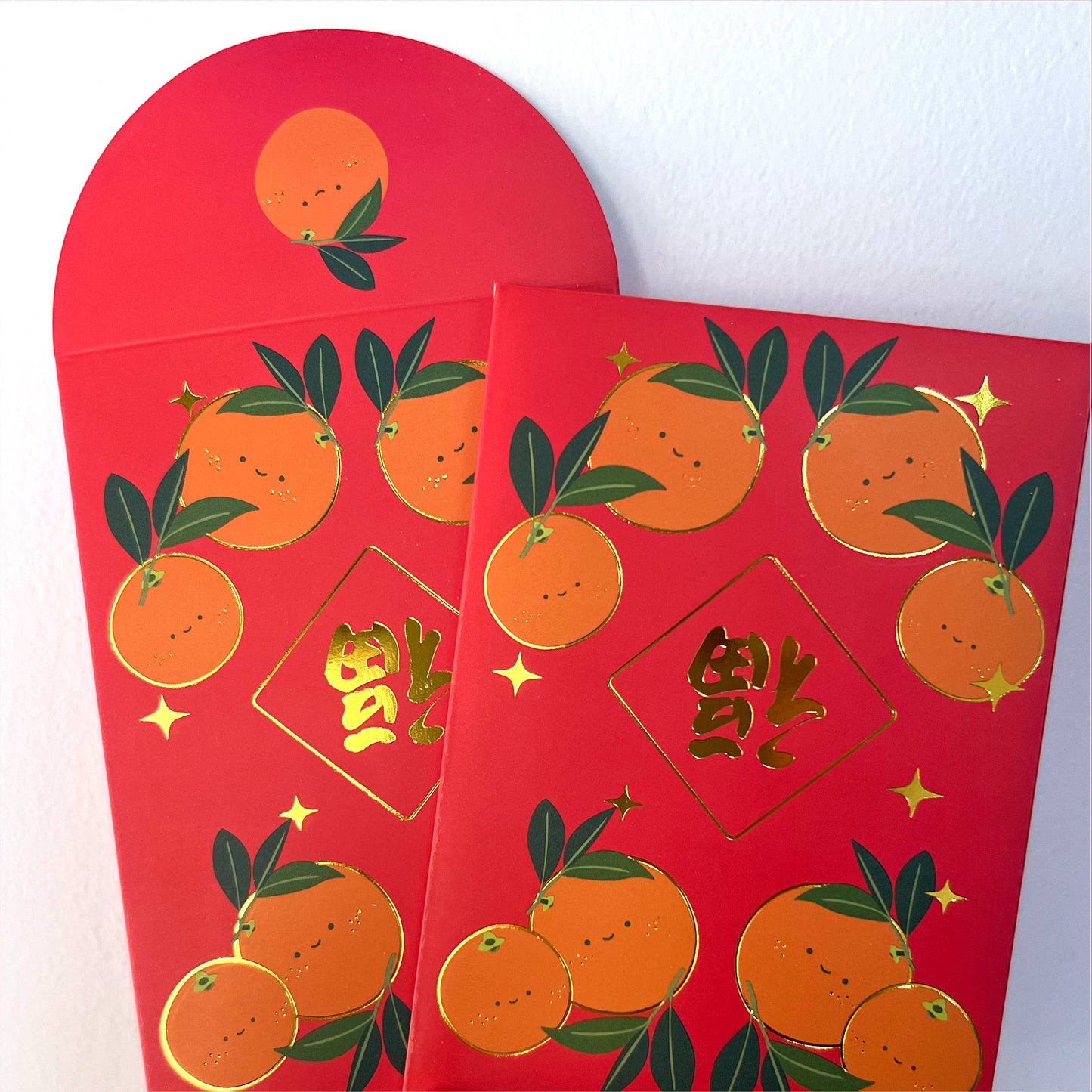 Gold foiled red envelopes with happy oranges on them 