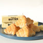 Pile of four croissant candles on a plate next to slabs of butter.