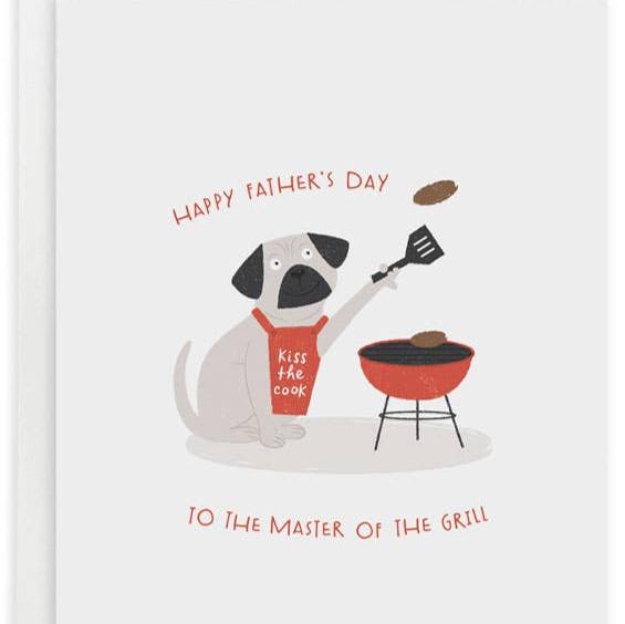 Father's day greeting card reads "Happy Father's Day to the master of the grill" and has a pug wearing a red apron that says "kiss the cook" and is grilling patties on the barbecue