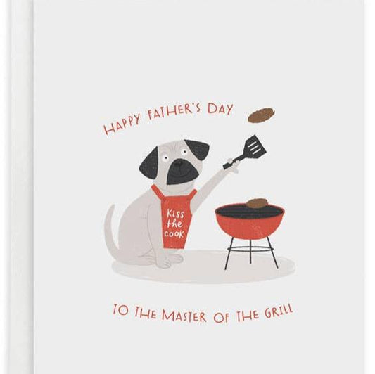 Father's day greeting card reads "Happy Father's Day to the master of the grill" and has a pug wearing a red apron that says "kiss the cook" and is grilling patties on the barbecue